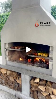 an outdoor pizza oven with firewood stacked in front and the words flame on it