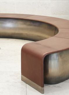 a curved bench sitting on top of a white tiled floor