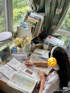 a woman sitting at a desk in front of a window with headphones on her ears