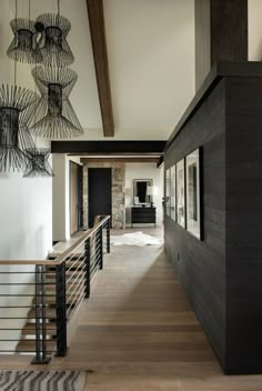 a large open floor plan with wood floors and metal handrails, along with chandeliers hanging from the ceiling