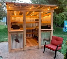 a small wooden structure with two red chairs in front of it and lights on the roof