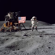 an astronaut standing on the moon next to a flag and other items in front of him