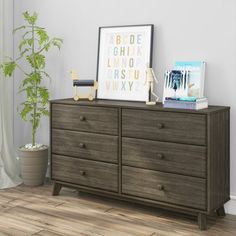 a bedroom with a dresser and pictures on the top shelf next to a potted plant