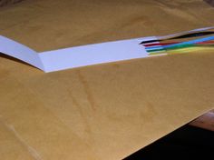 an open brown envelope with several colored pencils sticking out of the paper on top