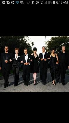 a group of people in black suits and ties walking down the street with their hands on their hips