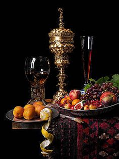 a table topped with fruit and candlesticks on top of a black table cloth