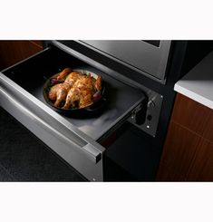 a pan filled with food sitting on top of an open oven door in a kitchen