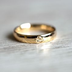 a yellow gold wedding ring with a diamond on the inside of it, sitting on a wooden surface