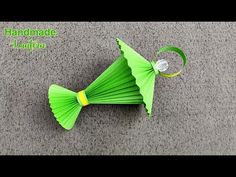 an origami fish made out of green paper on the ground with a tag attached to it