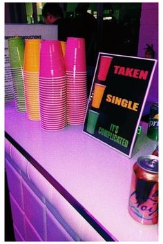 there is a table with neon colored cups on it and a sign that says taken single