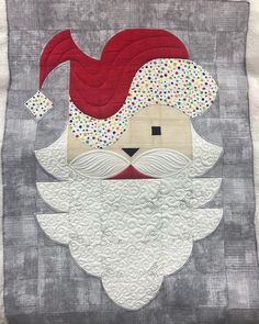 a quilted santa clause with a beard and mustache on it's face is shown