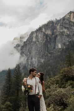 a bride and groom standing in the mountains