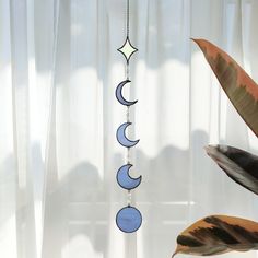 a wind chime hanging in front of a window next to a potted plant