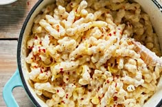 macaroni and cheese is being cooked in a blue pot with a wooden spoon