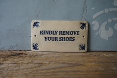 a sign that says, kindly remove your shoes on the side of a wooden table