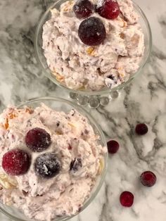 two bowls filled with food sitting on top of a marble counter next to cranberries