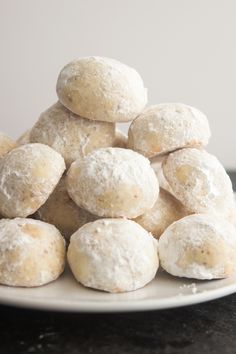 powdered sugar donuts stacked on top of each other in front of a white plate