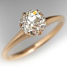 an old mine cut diamond sits in a yellow gold ring