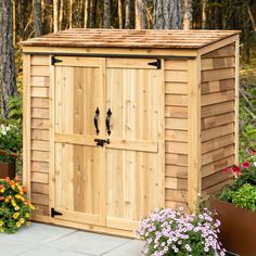 a wooden storage shed with flowers in the foreground