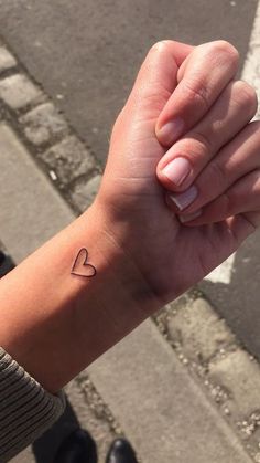 a woman's arm with a small heart tattoo on it