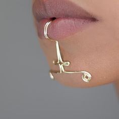 a close up shot of a woman's nose wearing gold ear cuffs and piercings