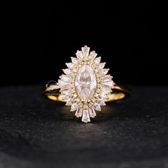 a yellow gold ring with an oval cut diamond surrounded by small white diamonds on a black surface