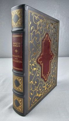 an old book with gold and red covers