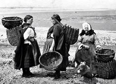 an old black and white photo of people walking in a field with spears on their heads