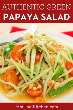 a white plate topped with green papaya salad next to a red and white table cloth