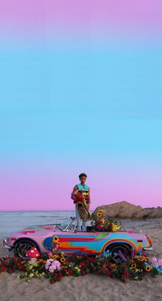 a man riding on the back of a car covered in flowers next to the ocean