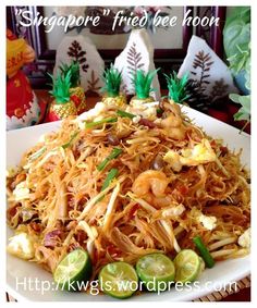 a white plate topped with noodles and shrimp next to pineapples on a table