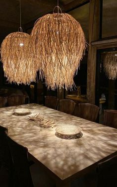 a dining room table that has some plates on it and lights hanging from the ceiling