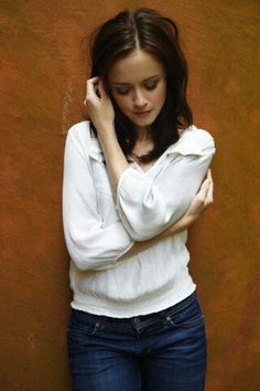 a woman leaning against a wall with her hand on her head