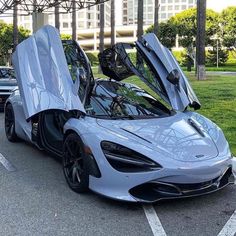 a silver sports car with its doors open in a parking lot next to other cars