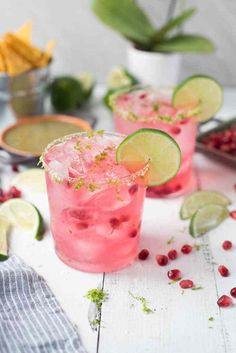 two glasses filled with pink lemonade, lime and pomegranate garnish