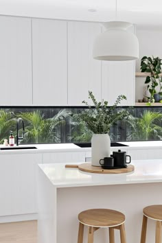 a kitchen with two stools next to a counter top and potted plants on the window sill