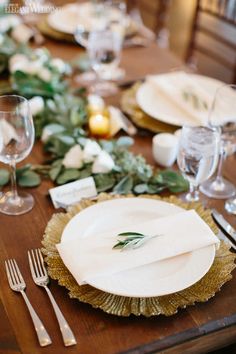 a wooden table topped with white plates and silverware