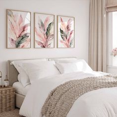 two paintings on the wall above a bed in a room with white sheets and pillows