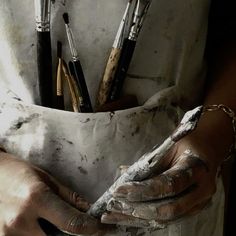 a person holding paintbrushes in their hands while they are covered with white paint