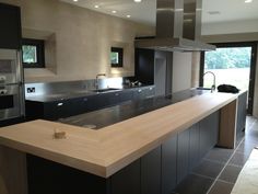 a modern kitchen with an island counter and stainless steel appliances in the center, along with black cabinets