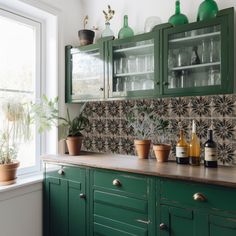 a kitchen with green cabinets and plants in the window sill, potted plants on counter