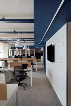 an office with desks, chairs and a whiteboard on the wall in front of it