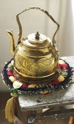 a gold tea pot sitting on top of a wooden table