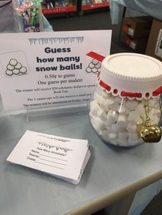 a glass jar filled with marshmallows sitting on top of a table next to a sign