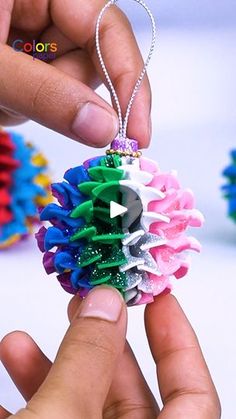 a person is holding a colorful ornament in their hand and it looks like they are making something out of paper