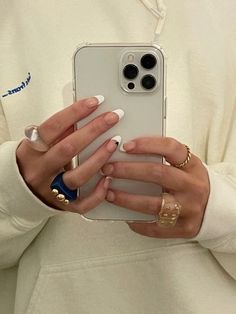 a woman holding up her cell phone to take a selfie with her ring fingernails