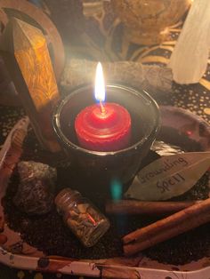 a lit candle sitting on top of a bowl filled with rocks and cinnamon stick sticks