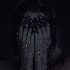 a woman with her hands covering her face in front of her face is covered by black veils