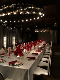 a long table is set with white linens and red napkins