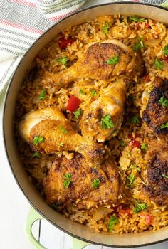 chicken and rice dish in a pan on a white tablecloth with green napkins